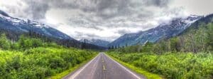 Car driving on a scenic mountain highway through green forested hills
