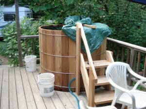 Private outdoor hot tub on a wooden deck surrounded by garden greenery