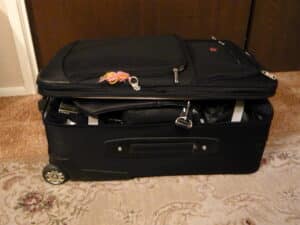 Open suitcase being packed with clothes and travel essentials for a trip
