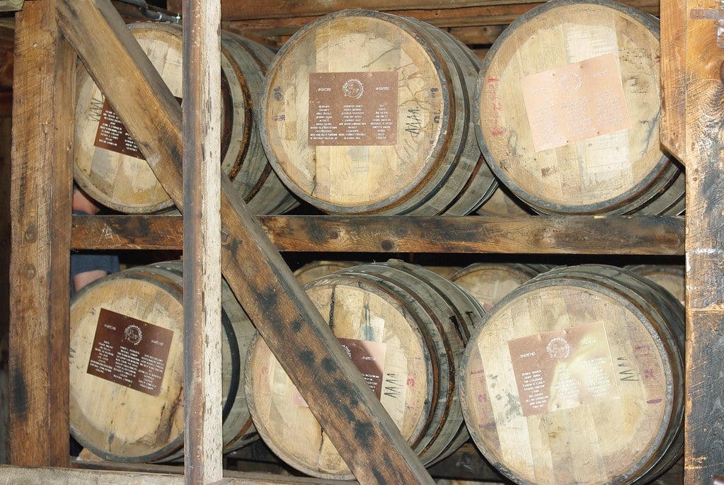 Row of wooden whiskey barrels stacked in a distillery warehouse